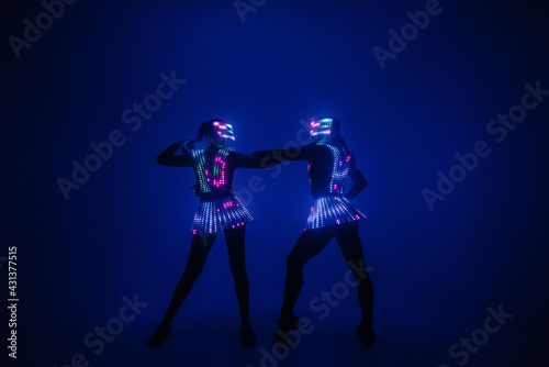 Two sexy disco dancers move in UV costumes. Parties and dances. © Andrii