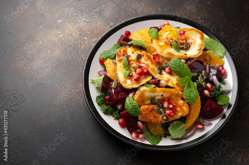 Fried Halloumi Cheese salad with beetroot, orange, pomegranate and pumpkin seeds, red onion, green vegetables. healthy food