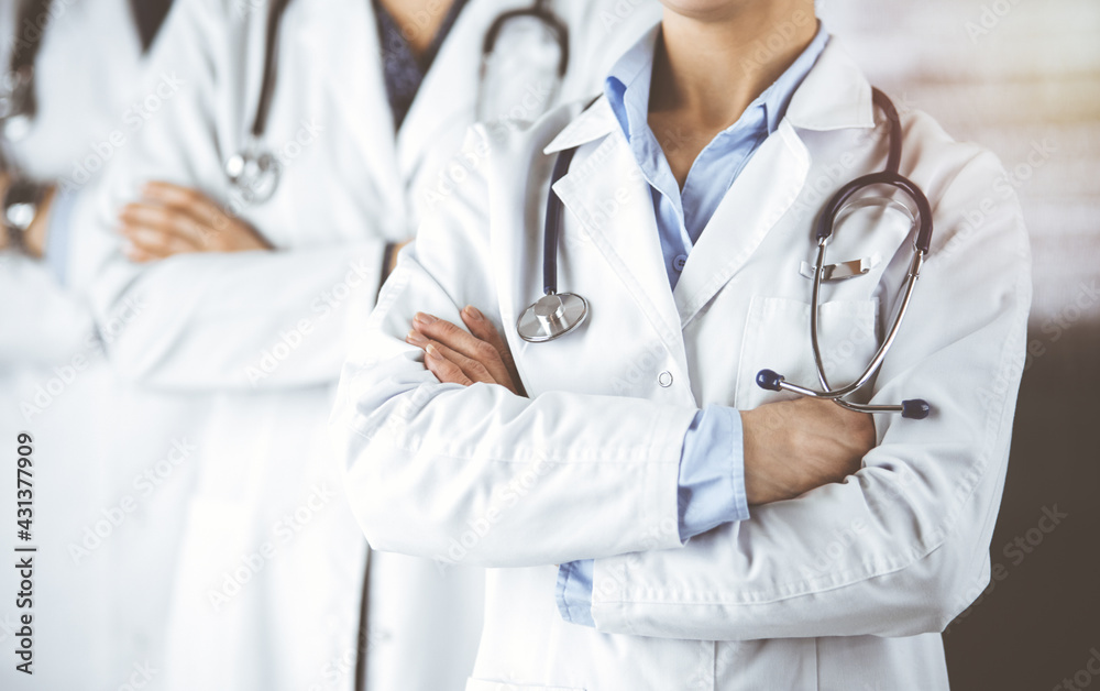 Group of modern doctors standing as a team with arms crossed in sunny hospital and ready to help patients. Medical help, insurance in health care Group of modern doctors standing as a team with arms crossed in sunny hospital and ready to help patients. Medical help, insurance in health care