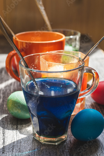 Preparing for the Easter holiday. Coloring eggs in the home kitchen in bright colors. Colored solution in glasses and cups.