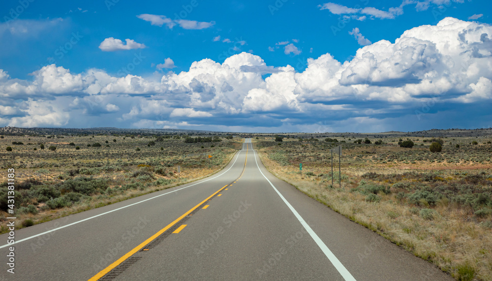 Highway in countryside USA. Empty national road, crossing American desert, Blue cloudy sky background