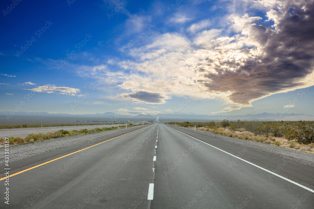 Highway in countryside USA. Empty national road, passing American desert, Blue cloudy sky background