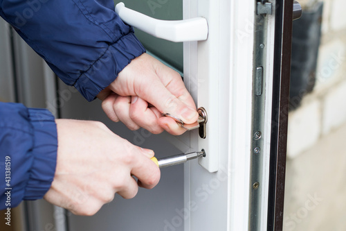 Handyman installing door lock in front door with screwdriver. Checking lock for operability in door.