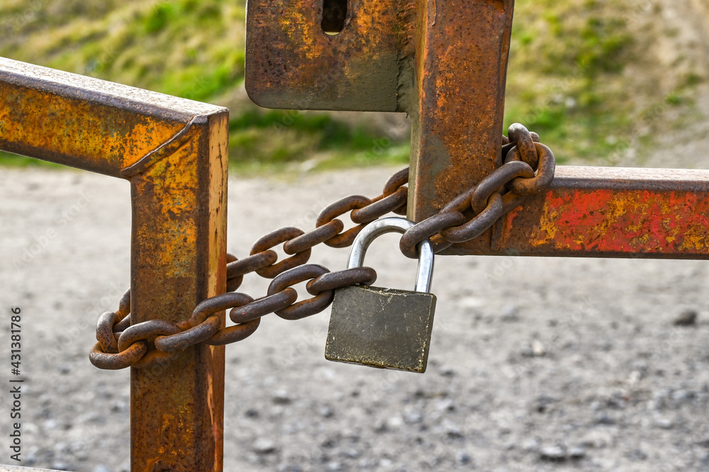 Close up view of a heavy metal chain secured around gates with a padlock. No people. Close up view of a heavy metal chain secured around gates with a padlock. No people.