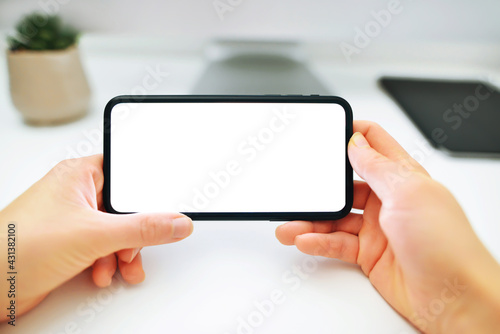 Mockup image of woman's hands holding and using a black mobile phone with blank screen horizontally for watching.