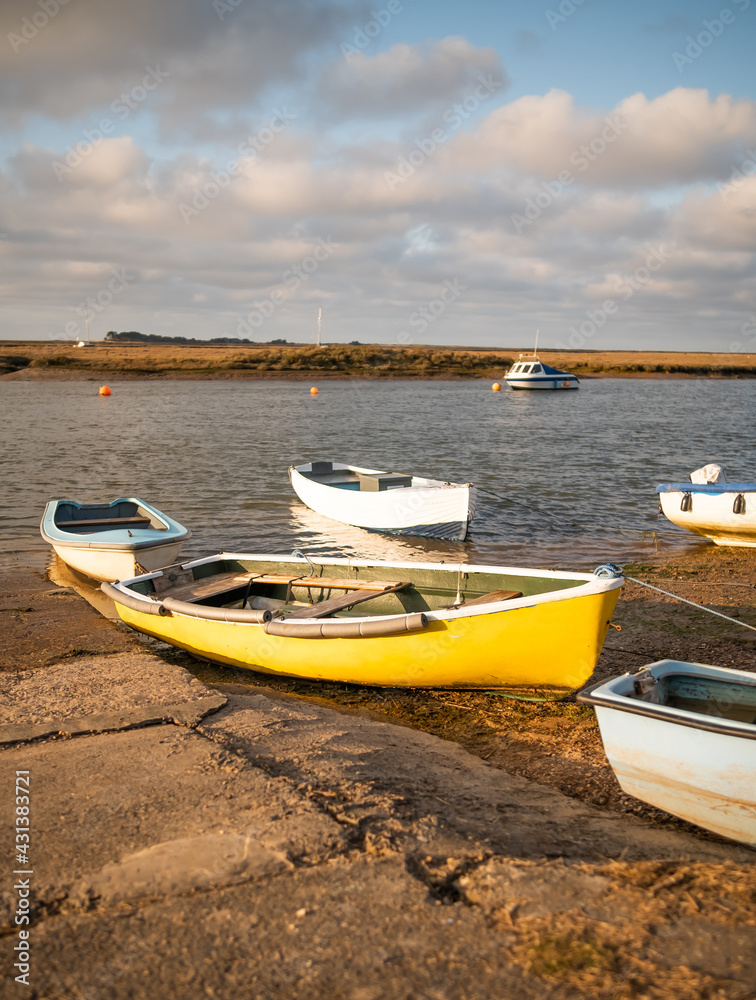 Small pleasure boats beached on the mud at low tide in Wells-Next-The-Sea estuary as the sun starts to set