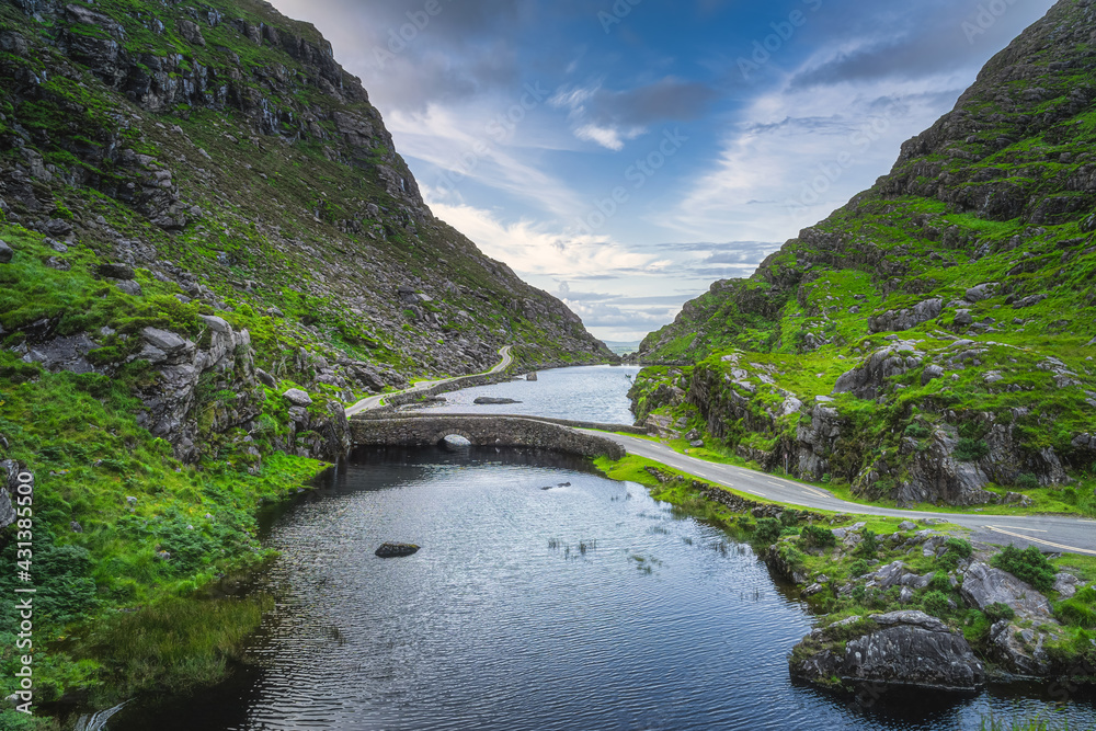 Winding narrow road crossing stone Wishing Bridge in Gap of Dunloe, Black Valley, MacGillycuddys Reeks mountains, Ring of Kerry, Ireland