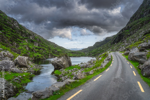Winding road running through Gap of Dunloe with stone Wishing Bridge in distance, Black Valley, MacGillycuddys Reeks mountains, Ring of Kerry, Ireland