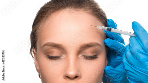 Beauty injections. Close-up view - gloved hands with a syringe inject Botox into the wrinkle area on the forehead.