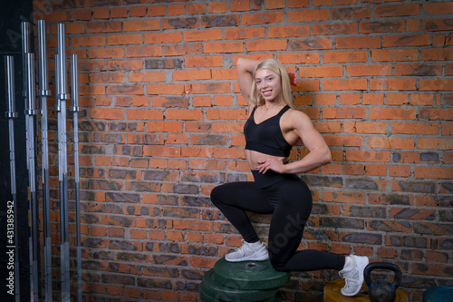 beautiful athlete posing against the background of a brick wall next to the bars and pancakes for the bar