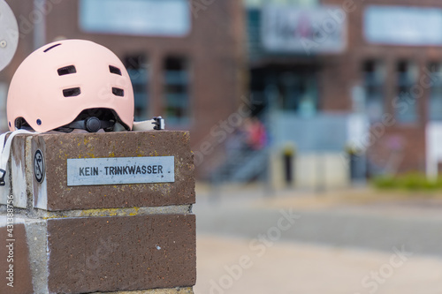 Mädchenfahrrad Helm auf der Randmauer eines öffentlichen Brunnens photo