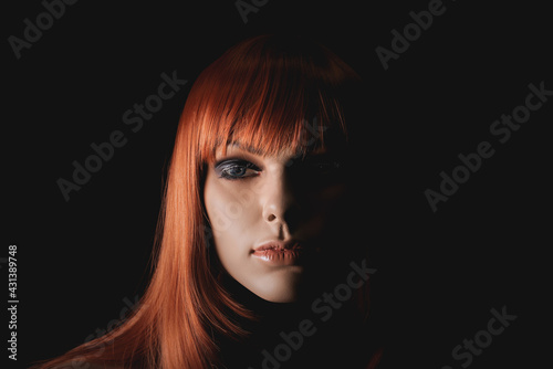 A beautiful female dummy with redhead wig on a black store showcase background.