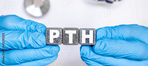 PTH Parathyroid hormone - word from stone blocks with letters holding by a doctor's hands in medical protective gloves photo