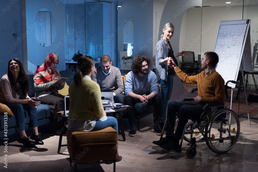 Office workers and handicaped person in a wheelchair discussing business moments in a modern office. Disability and business concept Office workers and handicaped person in a wheelchair discussing business moments in a modern office. Disability and business concept