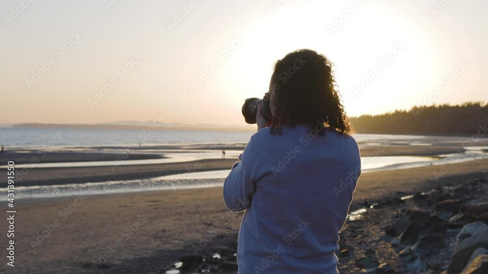 Adventure Travel Photographer at West Pacific Ocean Coast. Colorful Sunny Sunset. Adult White Caucasian Woman. Location: White Rock, Greater Vancouver, BC, Canada. Slow Motion Adventure Travel Photographer at West Pacific Ocean Coast. Colorful Sunny Sunset. Adult White Caucasian Woman. Location: White Rock, Greater Vancouver, BC, Canada. Slow Motion