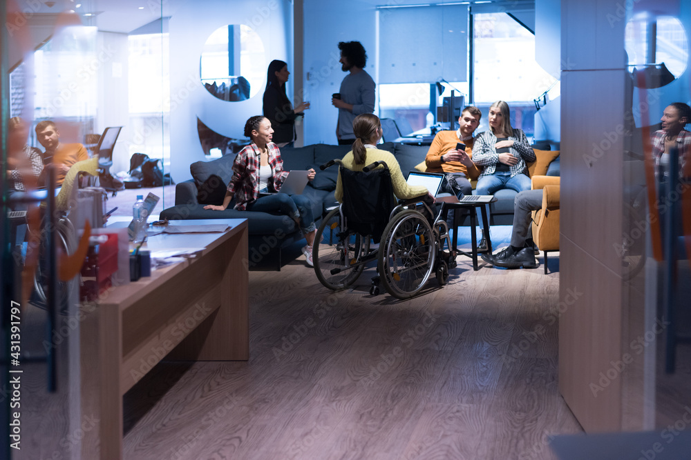 Office workers and handicaped person in a wheelchair discussing business moments in a modern office. Disability and business concept Office workers and handicaped person in a wheelchair discussing business moments in a modern office. Disability and business concept