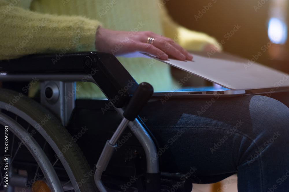 Young woman in wheelchair using computer laptop at modern workplace