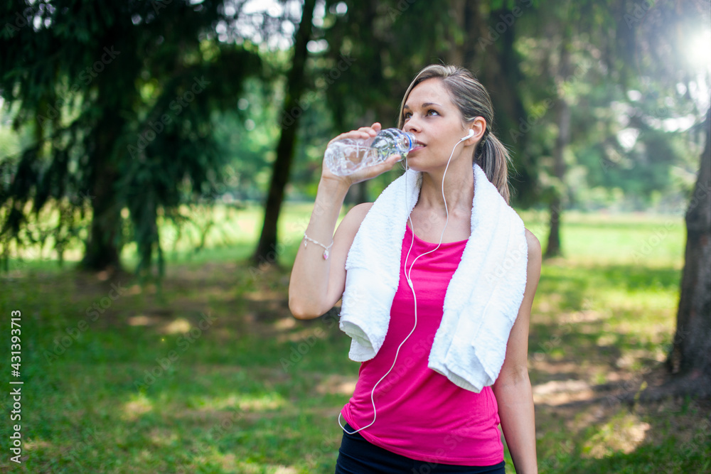 Woman drinking water after running at the park Woman drinking water after running at the park