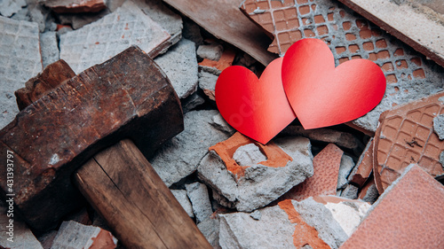 Two hearts among shards next to hammer. Concept of broken love. Unhappy relationships. Difficult period in family life. Quarrel. Endured scandal. Love against all odds. Infidelity and betrayal