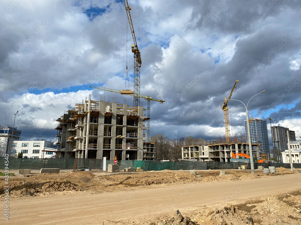 A large, high unfinished new building that is being built with the help of a construction industrial high-rise tower crane A large, high unfinished new building that is being built with the help of a construction industrial high-rise tower crane