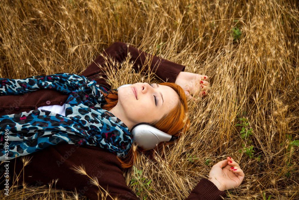 Young smiling fashion with headphones lying at field. Young smiling fashion with headphones lying at field.