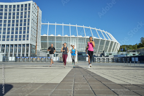 Young mixed racial athletes running on stadium background © Kostiantyn