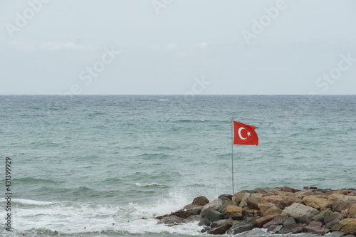 Turkish flag on the flag pole over the rocky pier 