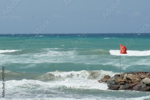 Turkish flag on the flag pole over the rocky pier in an windy day