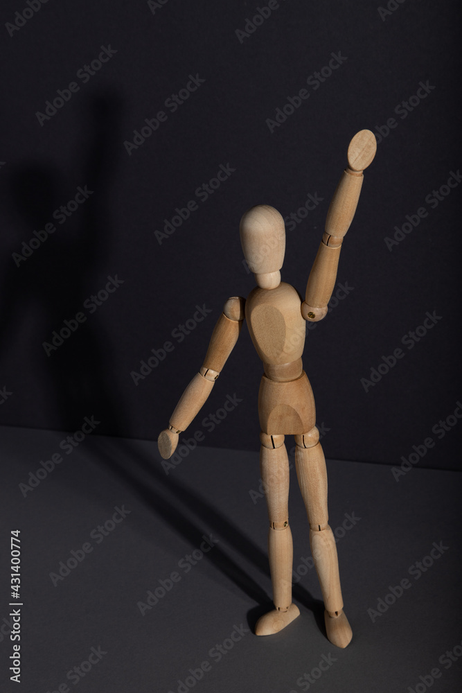 Wooden mannequin stands with raised hand on gray background. protest, attention concept. . copy space. Wooden mannequin stands with raised hand on gray background. protest, attention concept. . copy space.