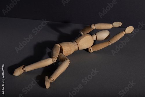 Wooden mannequin lies in a protective position on gray background. violence, depression disorder concept. copy space.