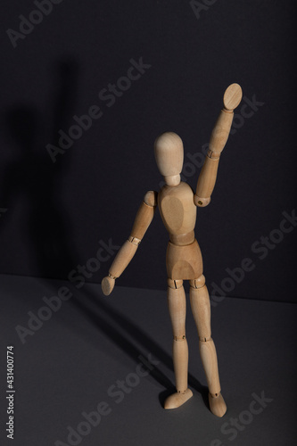 Wooden mannequin stands with raised hand on gray background. protest, attention concept. . copy space.