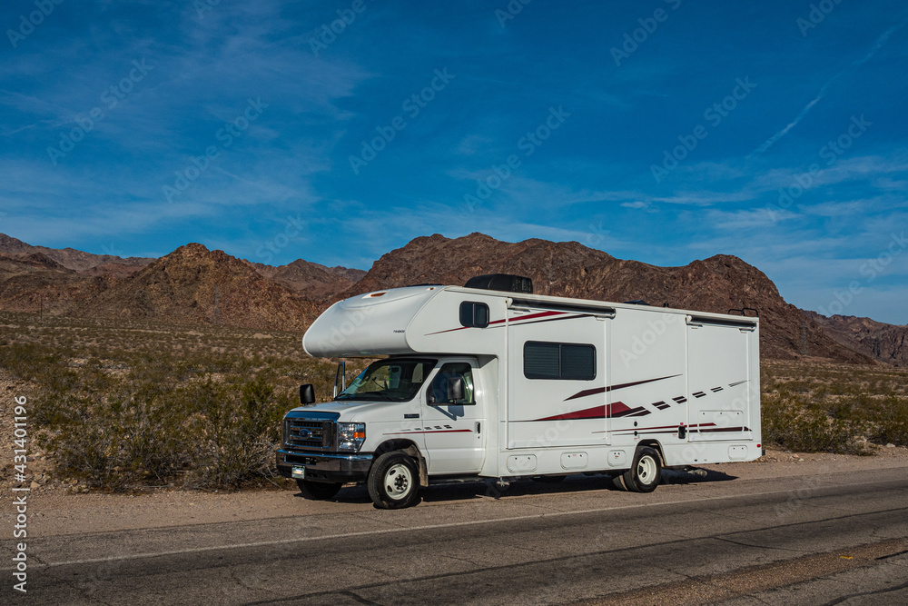 C-type camper with slideouts standing in the desert with mountains in the background