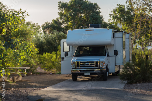 C-type camper with slideouts standing on the campground on concrete