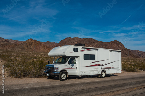 C-type camper with slideouts standing in the desert with mountains in the background