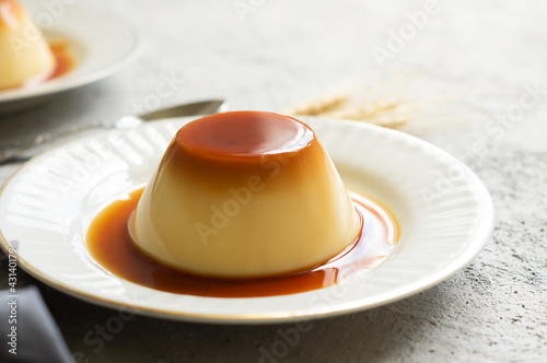 Cream caramel pudding with caramel sauce in plate on white rustic table photo