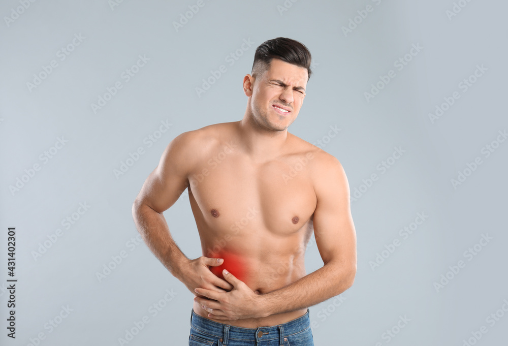 Man suffering from liver pain on grey background Man suffering from liver pain on grey background