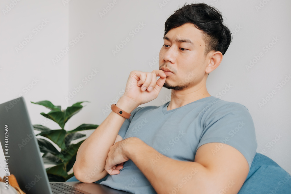 Serious Asian man work on computer laptop while stay at home. Serious Asian man work on computer laptop while stay at home.