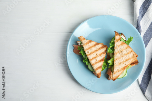 Blue plate with tasty sandwiches on white table, top view. Space for text