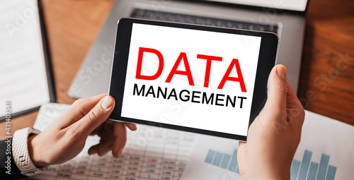 Man hands holding tablet with text DATA MANAGEMENT at workplace. Businessman working at desk with documents