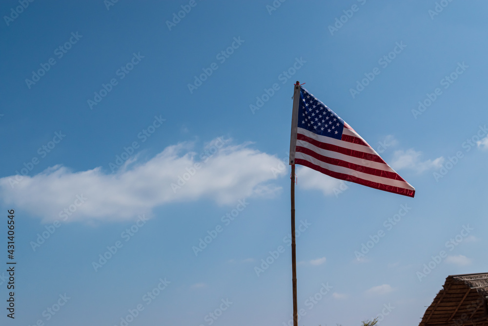 Flag of United States of America on the blue sky and cloud background