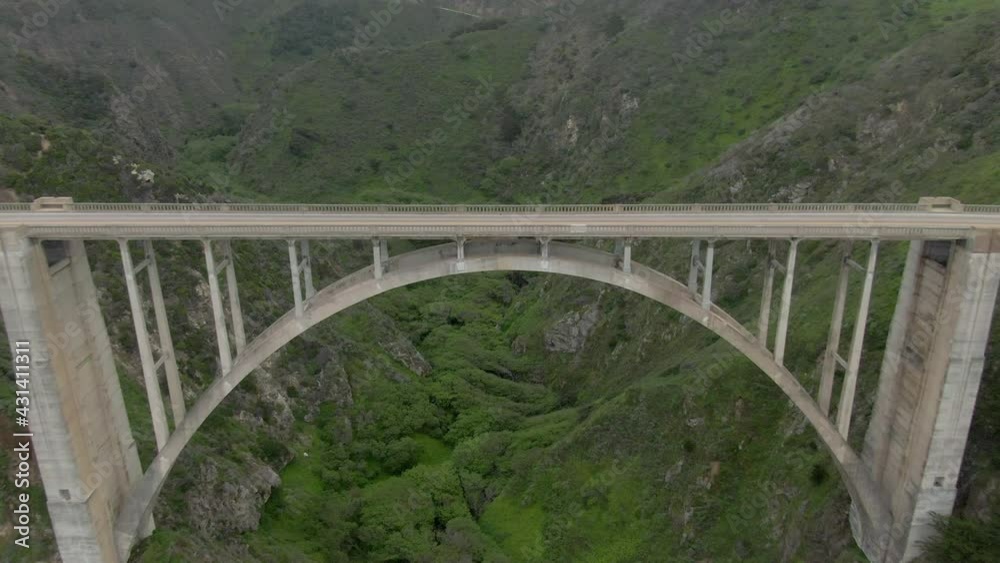 Aerial Shot Of Cars On Bixby Creek Bridge Against Green Plants, Drone Flying Backward Over Vehicles At Famous Landmark - Big Sur, California Aerial Shot Of Cars On Bixby Creek Bridge Against Green Plants, Drone Flying Backward Over Vehicles At Famous Landmark - Big Sur, California