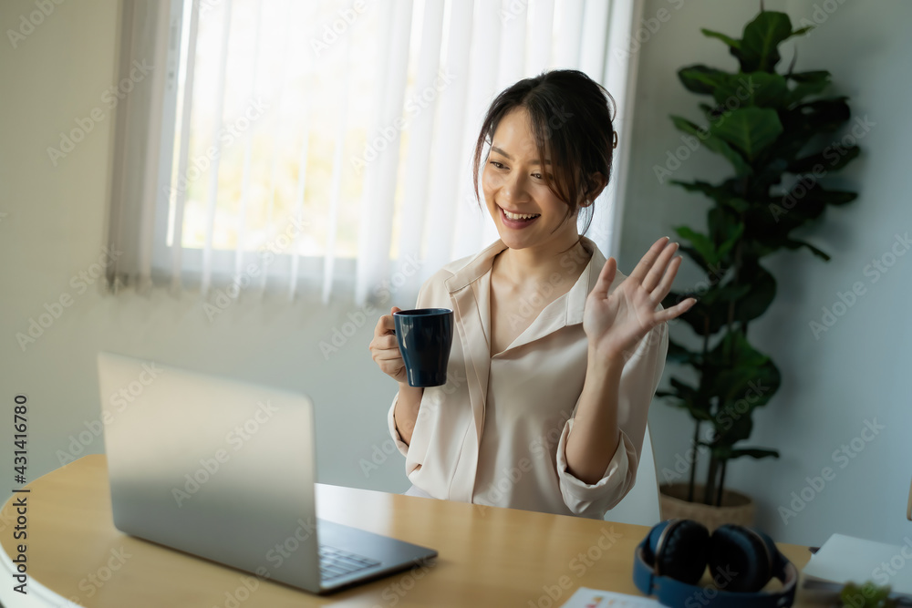 Joyful businesswoman sitting at desk looking at laptop screen talking with friend make informal video call Joyful businesswoman sitting at desk looking at laptop screen talking with friend make informal video call