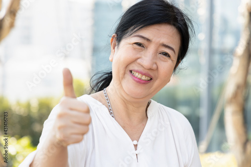 Old asian senior woman giving yes, ok, approving thumb up gesture