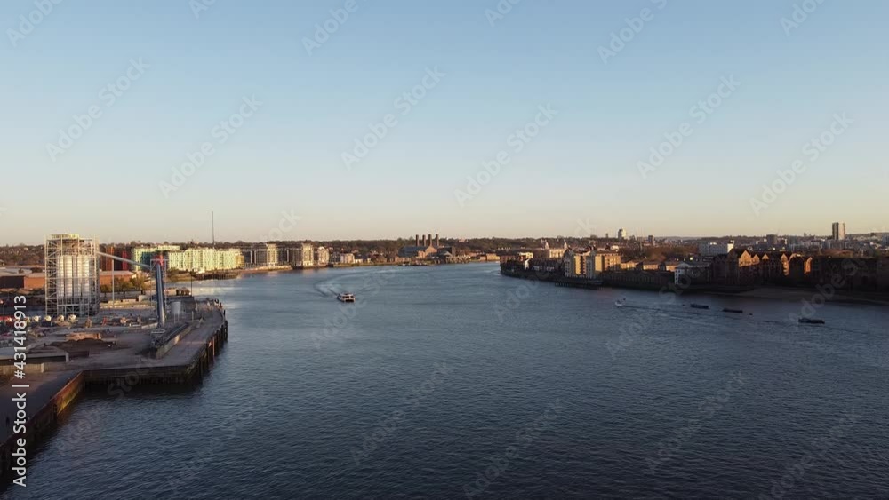 Aerial view of River Thames with cruising boat during sunset and construction site on shore. London,Uk. Aerial view of River Thames with cruising boat during sunset and construction site on shore. London,Uk.