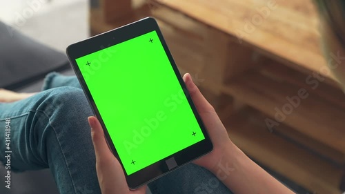 Close up of woman holding in hands a digital tablet with green screen for internet online, chroma key screen for advertising.