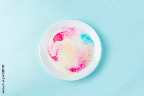 Fun kids science experiments. Step by step instruction: how to make colorful stains in milk. Step2 pour milk into a plate and add dye. Entertaining chemistry. photo