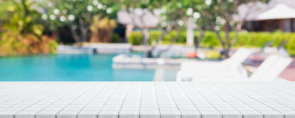 Empty white ceramic mosaic table top and blurred swimming pool in tropical resort in summer banner background - can used for display or montage your products.