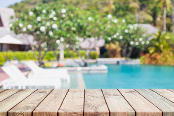 Empty wood table top and blurred swimming pool in tropical resort in summer banner background - can used for display or montage your products.