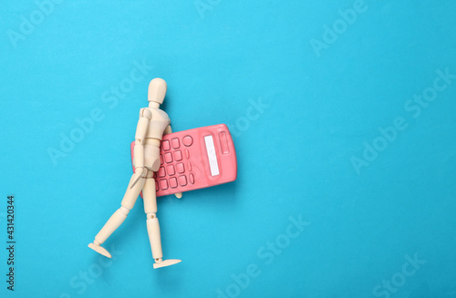 Quadro su tela Wooden puppet with a calculator on a blue background
