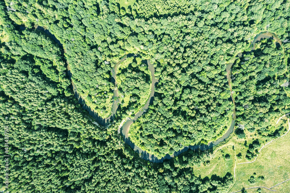 small winding river surrounded by green forest. aerial top view in summer day. small winding river surrounded by green forest. aerial top view in summer day.